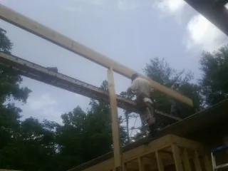 Carpenter setting a ridge beam over a new addition frame — Ice Dam Removal by Roofing Brothers in Village Mills
