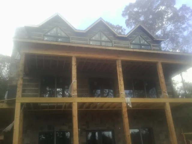 Dormers and porch framing on a large log home under construction — Roof Coating work by our crew in Village Mills
