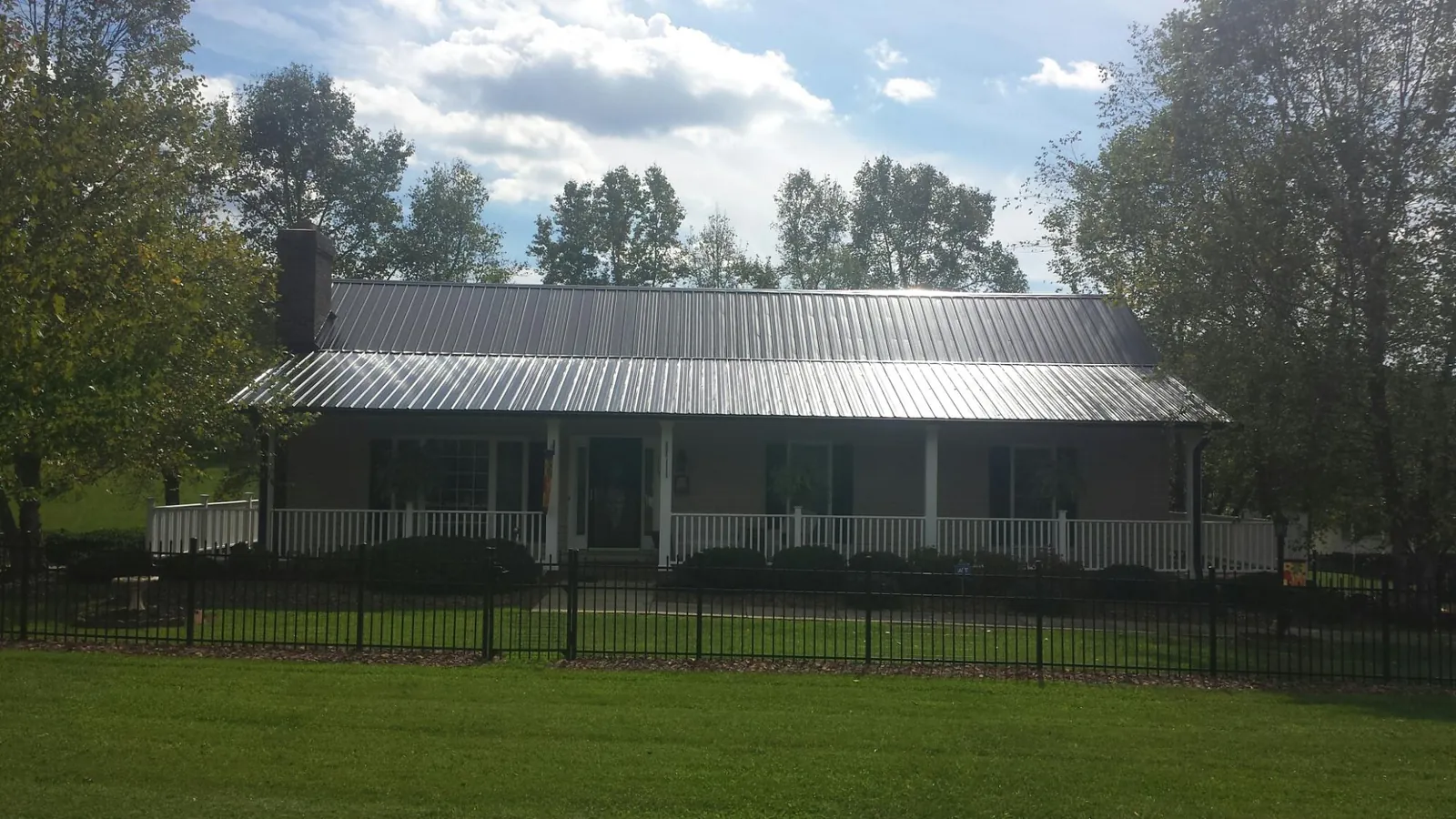 Gray metal roof on a brick ranch with a full width front porch — Gutter Guard Installation work by our crew in Village Mills