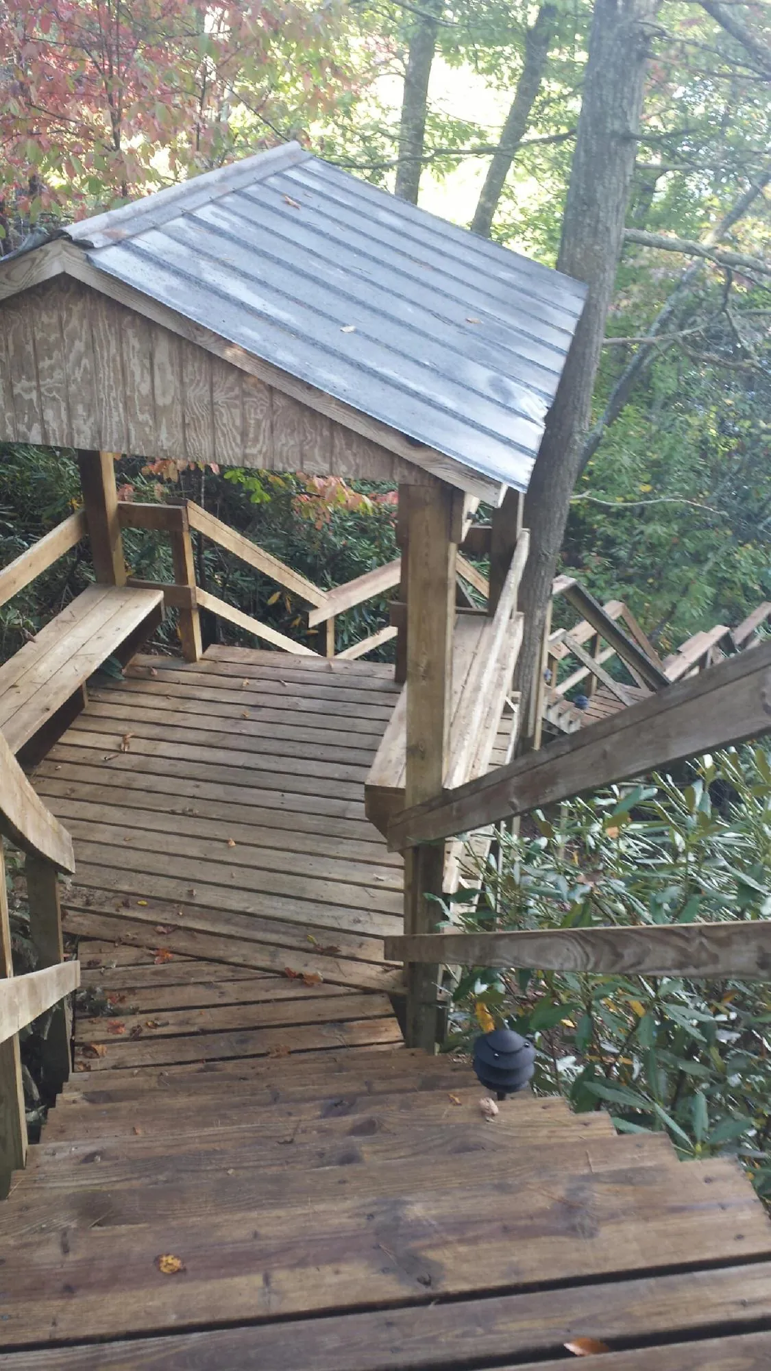 Metal roofed shelter over wooden steps on a wooded walkway — Skylight Repair & Installation work by our crew in Village Mills