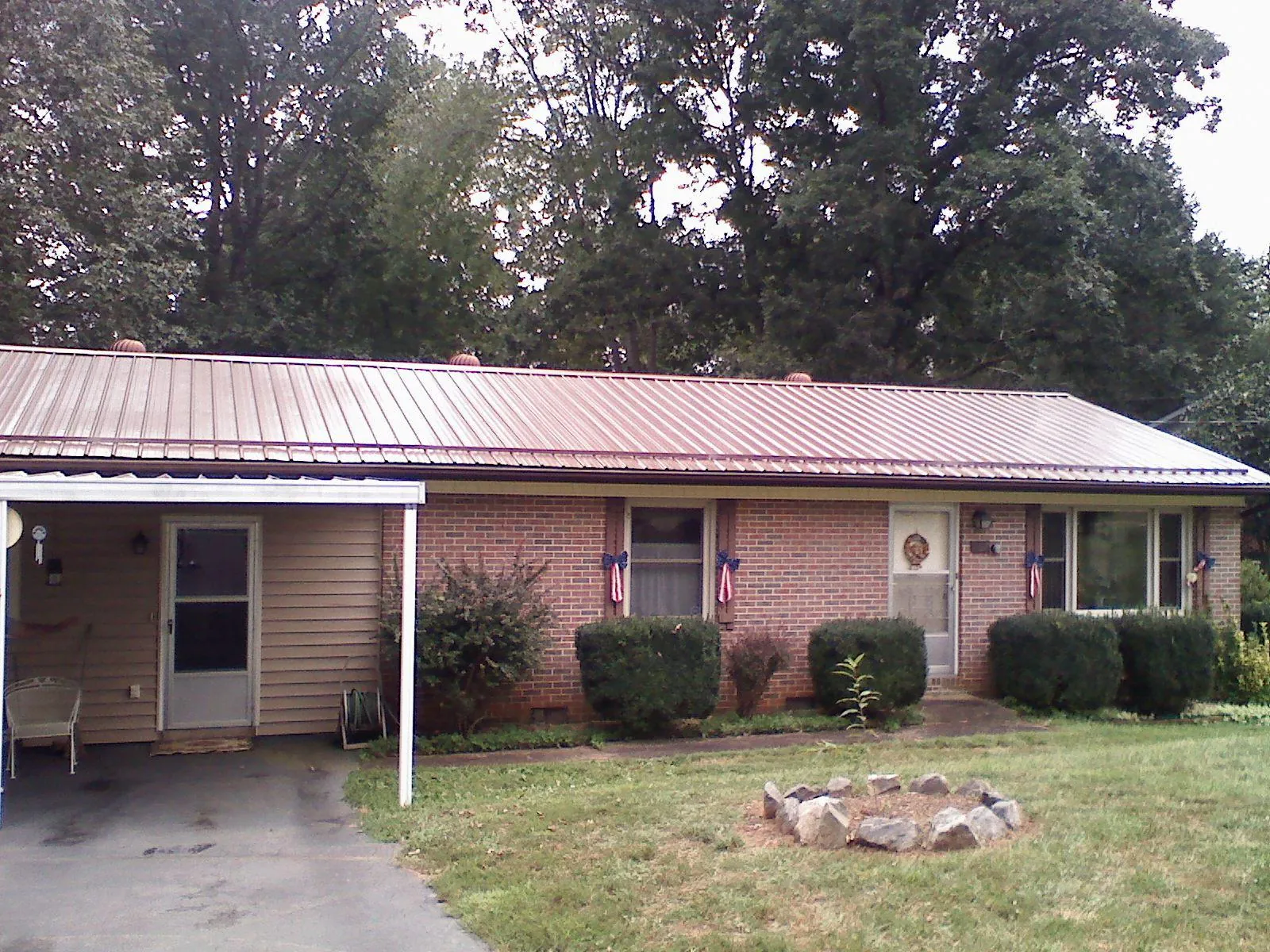 Bronze metal roof and carport on a brick ranch home — Roof Repair work by our crew in Village Mills