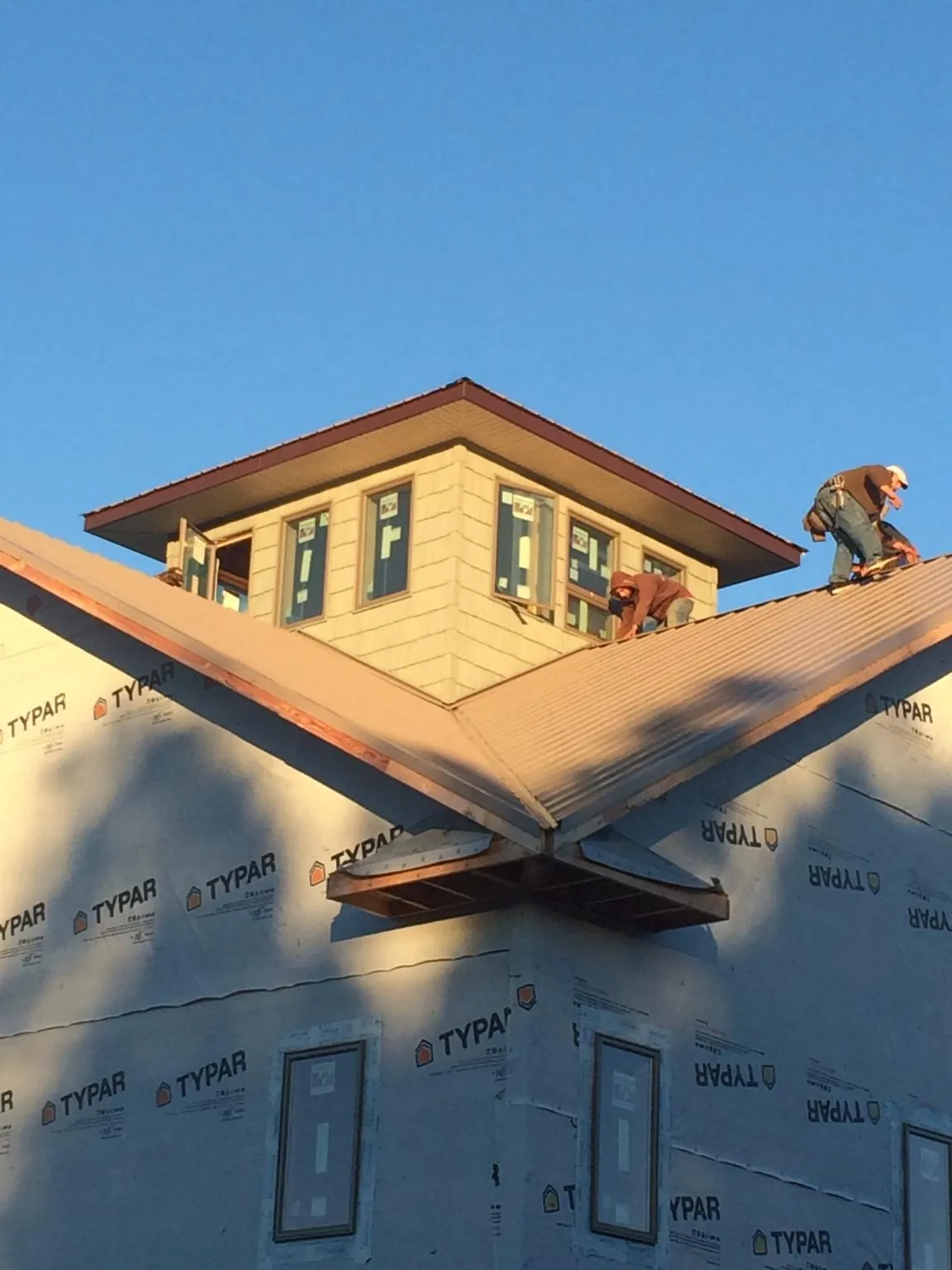Roofers working around a rooftop cupola on a new metal roof at sunset — Roof Waterproofing in Village Mills by Roofing Brothers